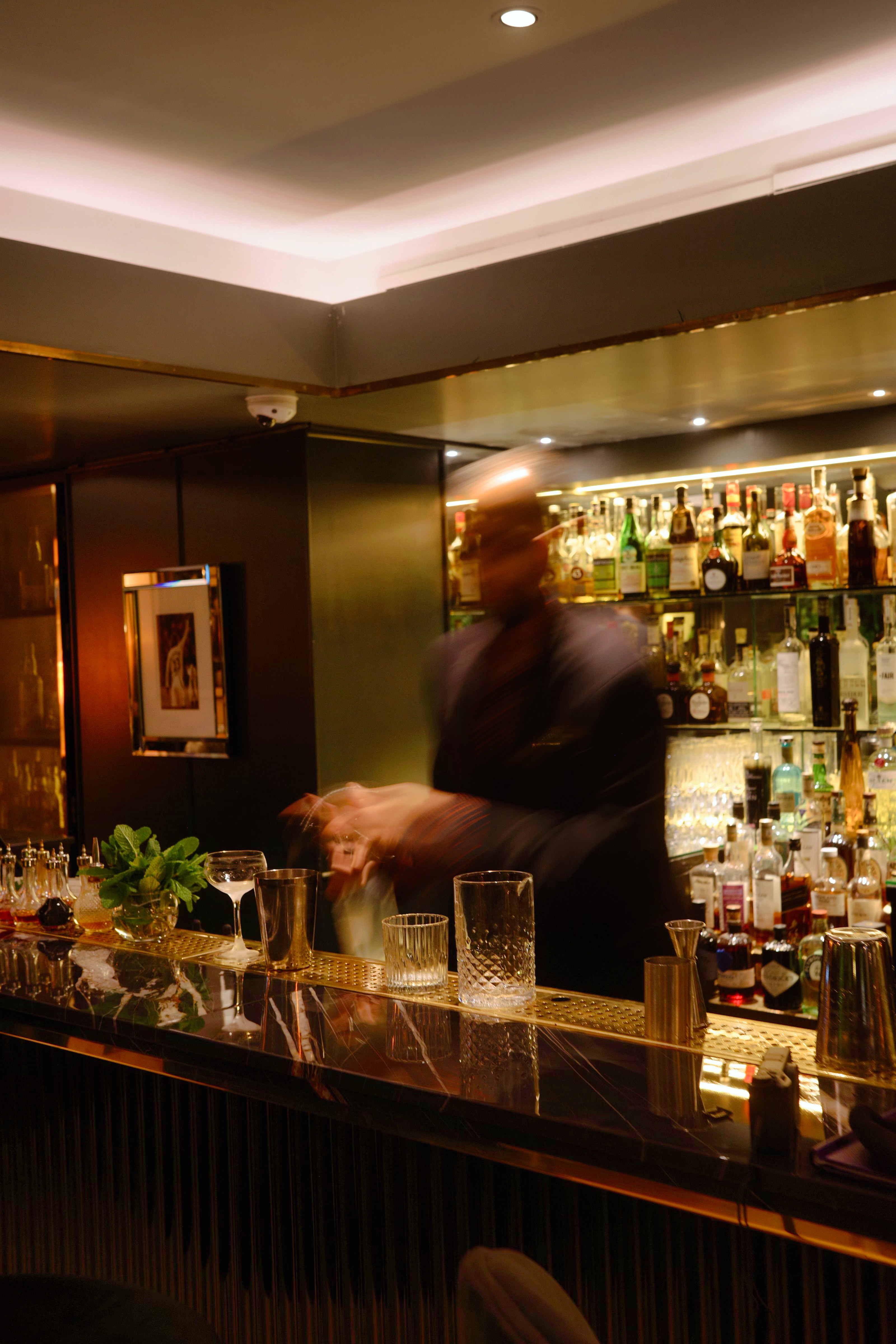 Bartender crafting cocktails behind the house bar