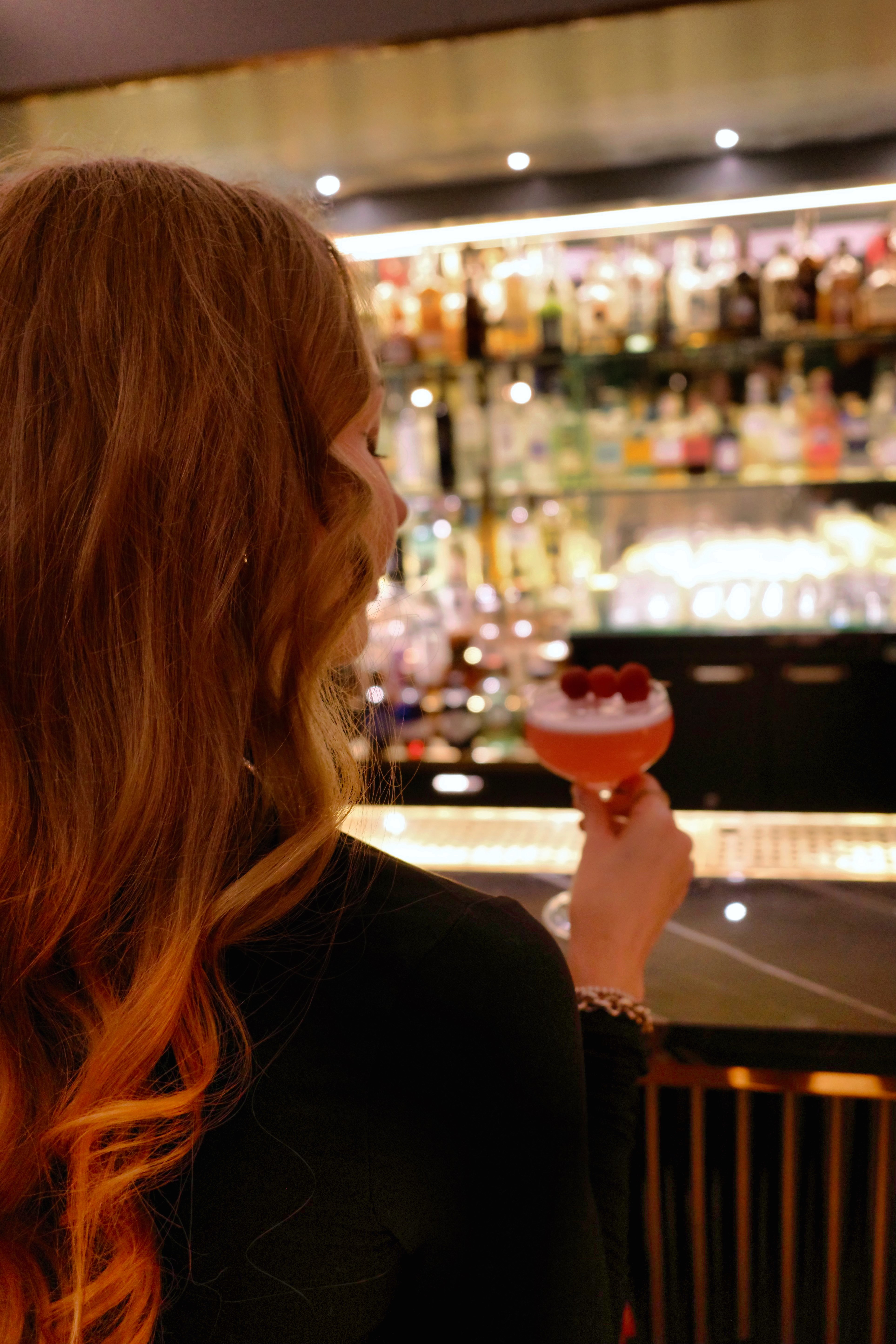 Guest enjoying a signature cocktail at the illuminated bar