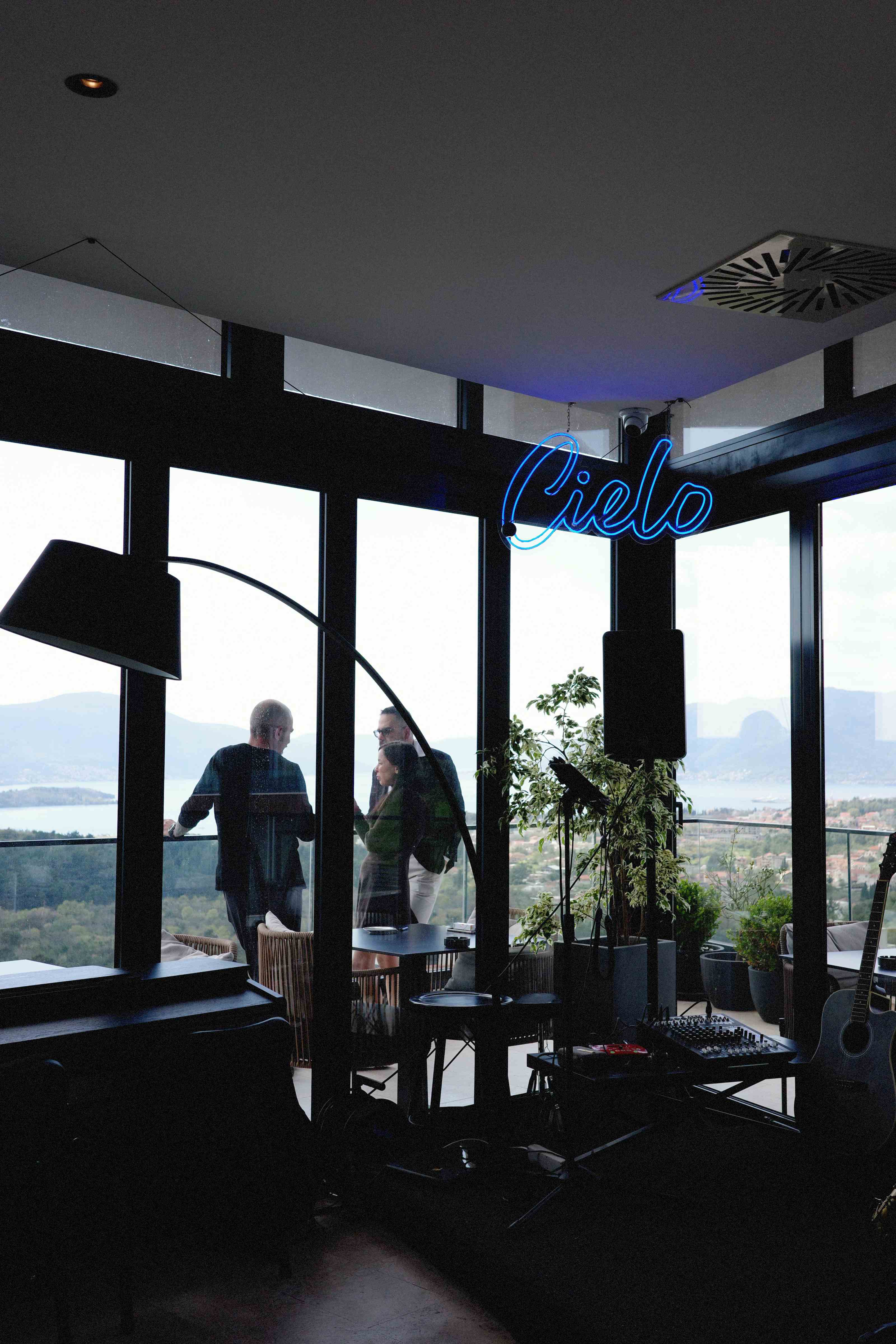 Rooftop Cielo lounge with blue neon sign and guests at Nomio