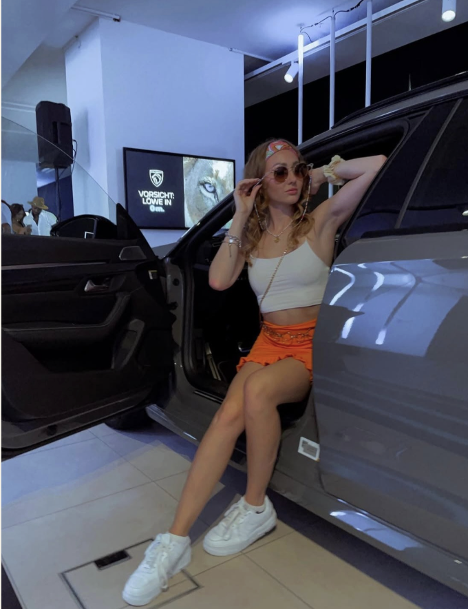 Woman posing with Peugeot convertible in showroom